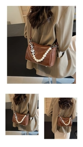 Detail einer braunen glänzenden Ledertasche mit dekorativer Perlen- und Herzkette Verzierung