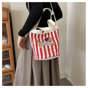 Détail du sac seau en toile à rayures rouges et blanches avec broderie petit chien