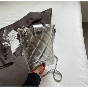 Detail of silver quilted bucket bag with chain strap and metal ball charm decoration