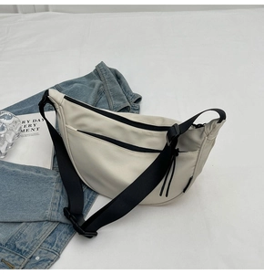 Detail view of cream dumpling crossbody bag with waterproof nylon texture and black strap