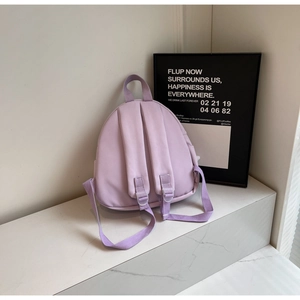 Detail view of purple canvas backpack showing adjustable shoulder straps and top handle