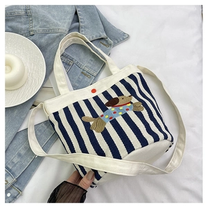 Détail du sac seau en toile rayée avec broderie de chien et bouton pression rouge