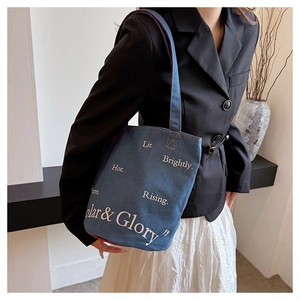 Dettaglio della borsa tote in denim blu scuro con scritte artistiche sulla modella