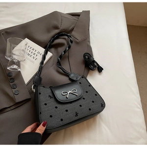 Detail einer schwarzen gepunkteten Handtasche mit silberner Schleife und gewebtem Riemen