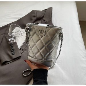 Detail of silver quilted bucket bag featuring a chain strap and metal turn-lock closure