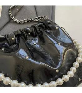Detail of black quilted PU leather bag with silver studs and elegant large pearl handle