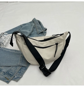 Detailed top view of ivory white dumpling bag showing waterproof texture and wide strap
