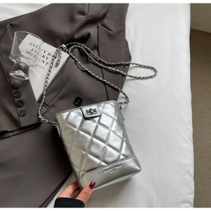 Close-up of silver quilted crossbody bag with metal chain strap and logo detail
