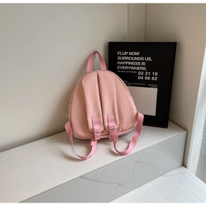 Rear view of pink nylon mini backpack with adjustable straps and top handle on marble table