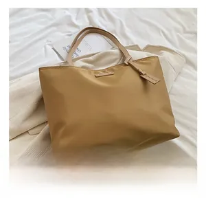Macro shot of khaki nylon tote bag texture and brand logo detail on white fabric