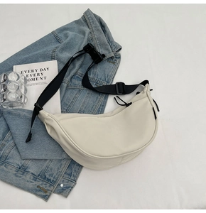 Top view of cream dumpling bag with adjustable black strap and minimalist accessories
