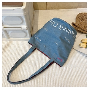 Dettaglio della borsa tote in denim blu con fodera a quadri rossi e neri e logo stampato