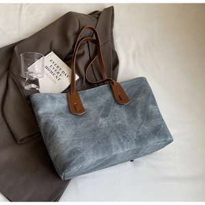 Close-up of a large grey-blue tote bag with brown leather straps for daily commute