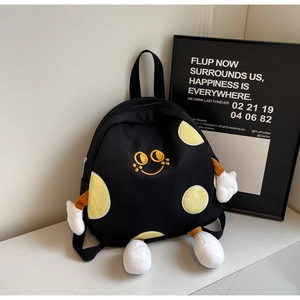 Detail of a black cartoon canvas backpack with a yellow smiling face and plush limbs