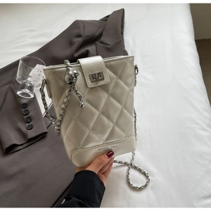 Detailed close-up of quilted cream bucket bag with silver metal chain and twist lock