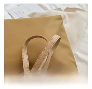 Close-up of litchi pattern leather handle on khaki nylon tote bag with stitching detail