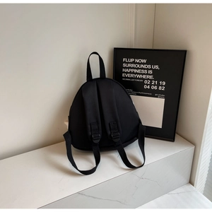 Rear view of black canvas mini backpack featuring adjustable straps on marble surface