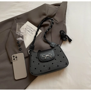 Details der schwarzen Polka-Dot-Handtasche mit silbernem Schleifenschloss auf Blazer