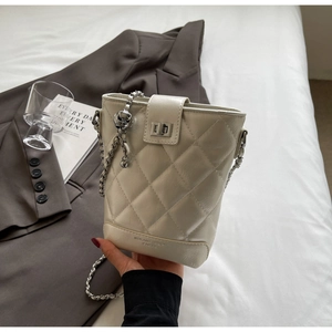 Close-up of beige quilted bucket bag with silver chain strap and metal swivel lock