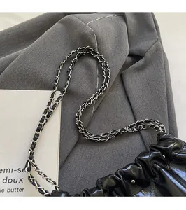 Close-up of glossy patent leather bucket bag with silver metal and leather chain strap