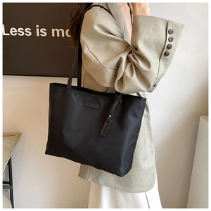 Close-up of black nylon tote bag showing smooth fabric texture and logo detailing