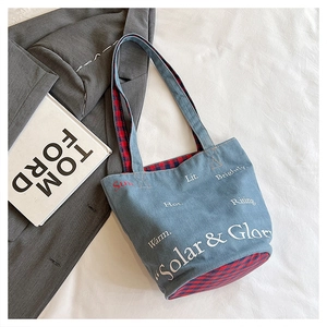 Dettaglio della borsa a secchiello in denim blu con stampa Solar & Glory e fodera rossa