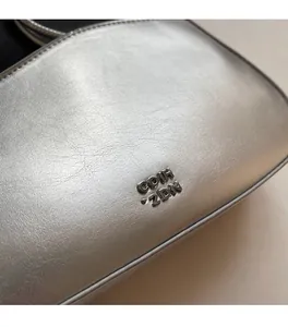 Close-up of metallic silver leather texture and premium gunmetal logo on shoulder bag