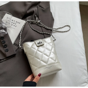Detail of white quilted chain bucket bag with pearl finish and gold-tone turn-lock closure