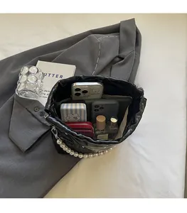 Detailed view of spacious black bucket bag interior with pearl chain and essentials