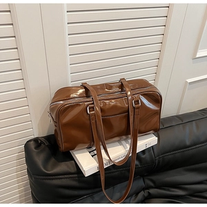 Detailed view of large brown glossy leather Boston bag with silver zipper in a modern home