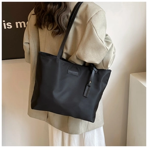 Detail of Carolpiatti black oxford tote bag with leather logo tag and waterproof fabric