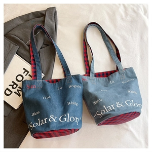 Dettaglio di borse tote in denim blu con stampa Solar & Glory e fodera a quadri rossi