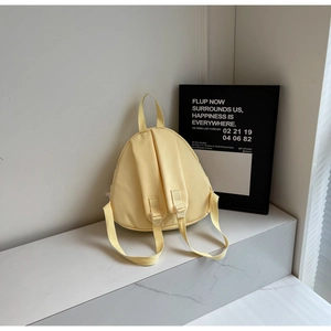 Detail of a light yellow triangular canvas backpack on a white marble surface