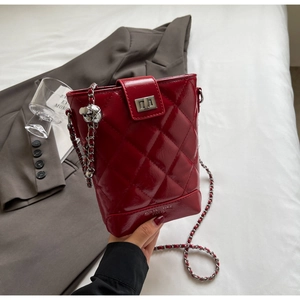 Detail of red quilted patent leather bucket bag with silver chain strap and logo