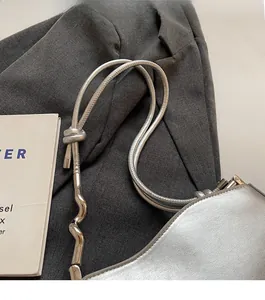 Detail of silver metallic shoulder bag showing wavy metal hardware and durable strap