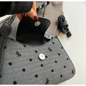 Detail der grauen Handtasche mit Punkten, Stickerei und magnetischer Metallschnalle