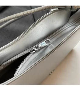 Close-up of smooth metal zipper and textured silver leather on a stylish shoulder bag