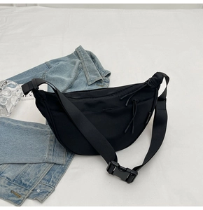 Detail of black crescent crossbody bag showing wide strap and durable buckle closure
