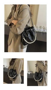 Detail view of black bucket bag with pearl handle and metal chain strap in use