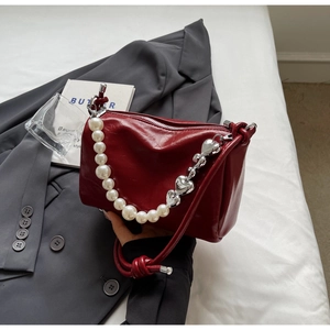 Detailansicht der weinroten Lackledertasche mit Perlen- und Silberherz-Kettendetail
