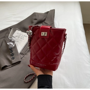 Detail of red quilted patent leather bucket bag with silver chain strap and metal clasp