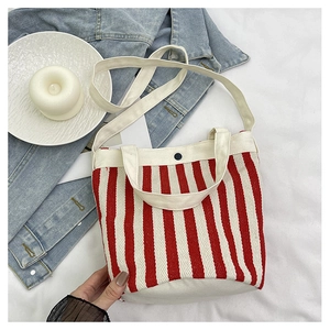 Détail du sac seau en toile à rayures rouges et blanches avec bandoulière et bouton pression