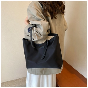 Close-up of black nylon tote bag showing spacious interior and premium leather handles