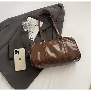 Detailed top view of a glossy brown leather bowling bag with vintage silver metal feet