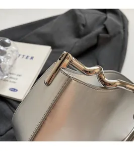 Detail of elegant wavy silver metal handle on a minimalist leather handbag