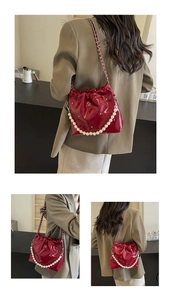 Detail of wine red pleated bucket bag featuring elegant pearl and metal chain straps