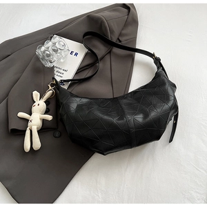 Detail of black geometric embossed hobo bag with a cute white rabbit plush keychain
