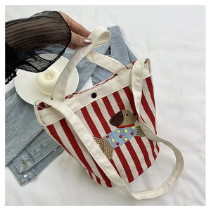 Détail du sac seau en toile à rayures rouges et blanches avec broderie chiot