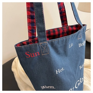 Dettaglio della borsa tote in denim con fodera scozzese e lettere stampate alla moda