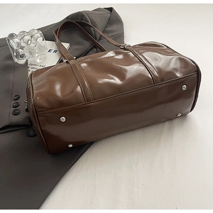 Macro view of brown patent leather bag showing bottom protective silver metal studs